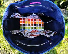 a blue purse with an orange and white patchwork design on the inside, sitting in grass