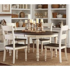 a dining room table and chairs with candles on top of the table in front of bookshelves