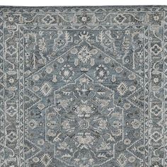 a blue rug with an intricate design on the front and back side, in grey tones