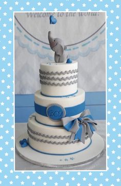 a blue and white cake with an elephant topper on it's tiers