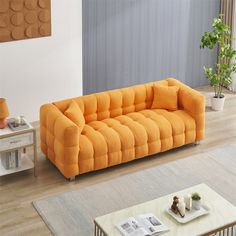 an orange couch sitting on top of a wooden floor next to a white coffee table