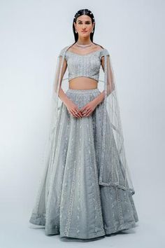 Silver lehenga hand embroidered with glass beads and stones. Paired with off-shoulder blouse. Comes with a net dupatta.
Component: 3
Pattern: Embroidered
Type Of Work: Glass beads, Stones
Neckline: Off-shoulder
Fabric: Silk organza, Net
Color: Silver
Other Details: 
Sheer dupatta
Hand embroidered motifs
Occasion: Reception, Destination Wedding - Aza Fashions Varun Chakkilam, Silver Lehenga, Embroidered Stripes, Silver Silk, Embroidered Lehenga, Embroidered Wedding, Wedding Lehenga, Net Dupatta, Indian Fashion Designers