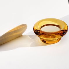 a glass bowl sitting on top of a white table next to a wooden object that looks like a banana