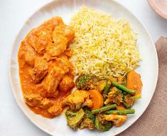 a white plate topped with rice and chicken next to broccoli covered in sauce