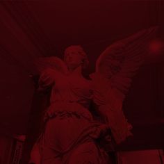 an angel statue with red lighting in the background