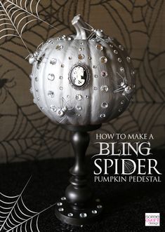 a silver pumpkin sitting on top of a black table next to a spider web net