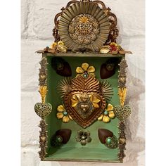 a green box with an ornate design on the front and sides, surrounded by other decorative items