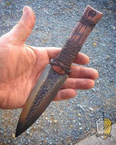 a hand holding a knife in it's palm with an intricate design on the blade