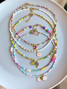 a white plate topped with lots of different colored beads and necklaces on top of it