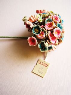 a small bouquet of flowers with a price tag attached to it on a white surface