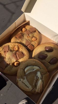 four cookies in a box with chocolate chips and marshmallows on the top