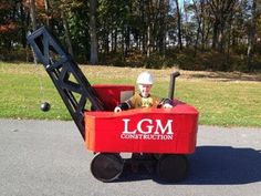 a small child in a red wagon with the word lgm construction on it's side