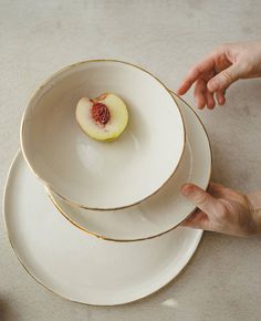 two white plates stacked on top of each other with a piece of fruit in the middle