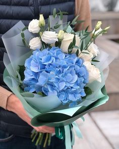 a person holding a bouquet of blue and white flowers