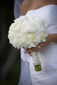 a bride holding a bouquet of white flowers