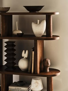 a shelf with vases, books and other items on it in a living room