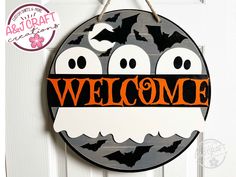 a welcome sign hanging on a door with bats and bats in the air above it