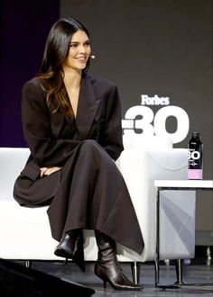 a woman sitting on top of a white couch in front of a tv screen and smiling