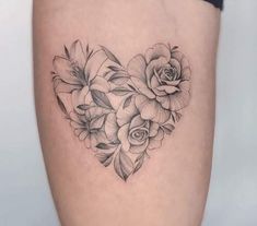 a heart shaped tattoo with flowers and leaves on the side of the thigh, in black and white