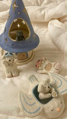 two small ceramic animals sitting next to each other on a bed