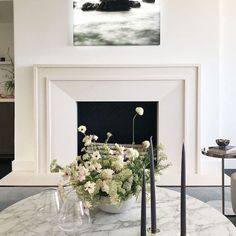 a vase with flowers sitting on top of a table next to a fire place in a living room