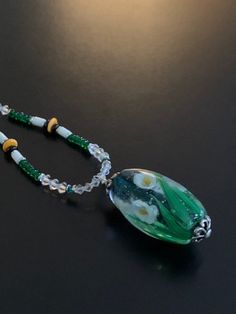 This is a stunning handmade lampwork floral bead by Ikuyoglassart measuring 1 3/4 inches long. The sides were beaded with clear swarovski bicones, deep green round beads, and white tube beads with a single yellow-orange rondelle bead to match the colors of the flowers. The 20 inch necklace is finished with black faceted beads which lead up to the sterling clasp. Petite gemstones are embedded in the end of the bar of the clasp. 20 Inch Necklace, White Tube, Tube Beads, In The End, Deep Green, Faceted Bead, Yellow Orange, Round Beads, Jewelry Necklace Pendant