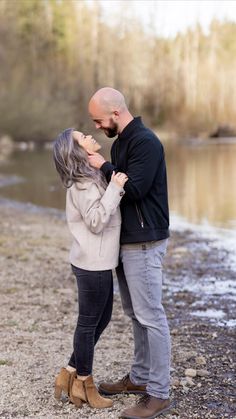 a man and woman standing next to each other near water