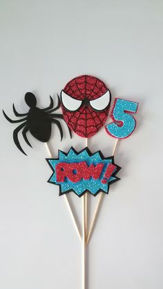 three spiderman cupcake toppers on a stick with the number five in it