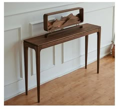 a wooden table with an old fashioned radio on it's top, in front of a white wall