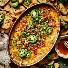 a casserole dish with green peppers and bacon on top surrounded by crackers