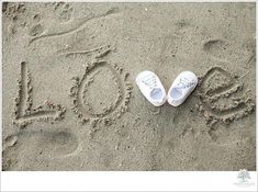 two pairs of white shoes sitting in the sand next to the word love written in the sand