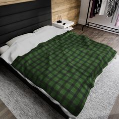 a bed with a green and black blanket on it's side in a bedroom