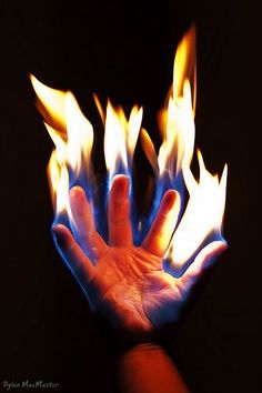 a person holding out their hand with fire in the middle and flames coming out of it