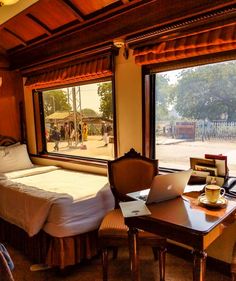 a bedroom with two beds and a desk in front of a window that looks out onto the street