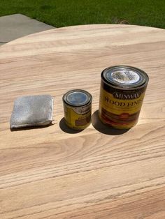 two cans of paint sitting on top of a wooden table