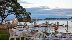 an outdoor dining area with tables and chairs overlooking the water