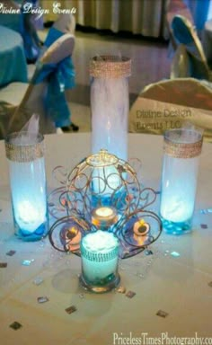 a table topped with two vases filled with blue liquid and lite up candles