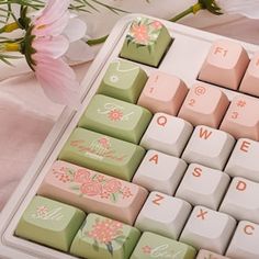 a keyboard with pink flowers on it sitting next to a white flowery table cloth