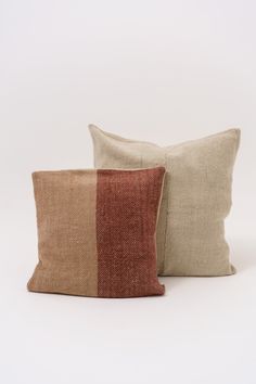 two pillows sitting next to each other on top of a white surface with red and tan stripes