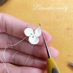 a person holding a pair of scissors in their left hand while they are working on some crochet