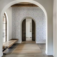 an arched hallway with wooden benches and wallpaper