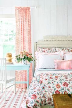 a bedroom with pink and white bedding, floral print comforter, striped rugs and curtains