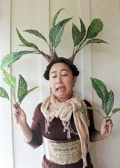 a woman is holding two plants in front of her face and making a funny face