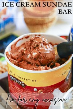 an ice cream sundae bar with chocolate frosting in a cup and spoon on the side