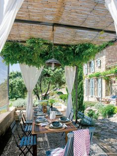 an outdoor dining area with table and chairs, covered in white draping over it