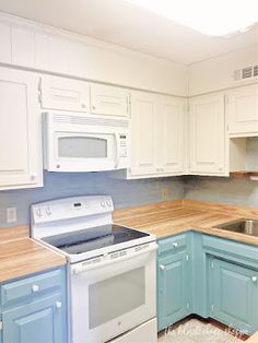 an empty kitchen with blue cabinets and white appliances, including a silver stove top oven