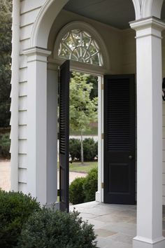 an open door to a white house with black shutters on the front and side