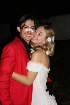 a man in a red suit hugging a woman in a white dress