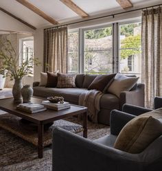 a living room with couches, chairs and a coffee table in front of large windows