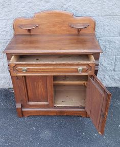 an old fashioned wooden desk with two doors and cupboards on the bottom shelf, in front of a white brick wall